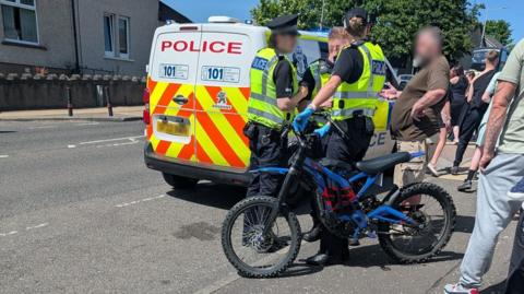 Police officers, a police van and an electric dirt bike