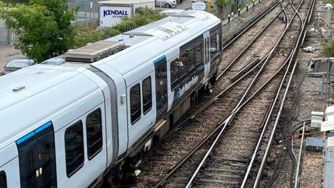 An SWR train in white and blue livery leaving a station.