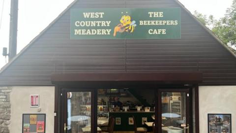 Exterior of the Beekeepers Cafe in Redhill, Bristol. Owner Rod Jenkins visible through open front doors. 
