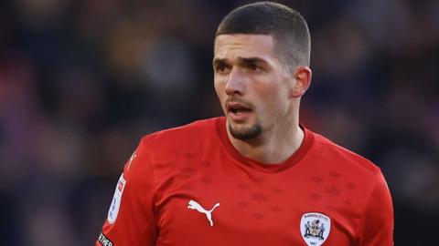 Max Watters in action for Barnsley. He is wearing a home red shirt.
