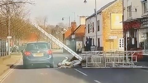 Scaffolding falling into the road and hitting a passing car.