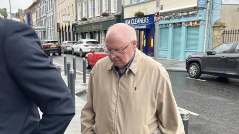 Canon Patrick McAntee entering court in Enniskillen, wearing a tan jacket