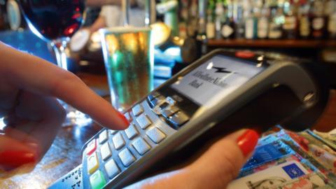 Woman paying by card for drinks in pub