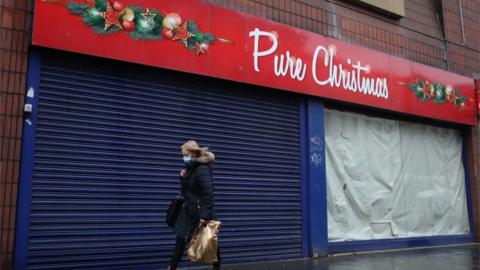 Woman walks past closed shop in Glasgow