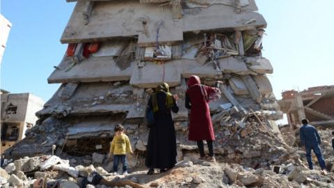 People stand among the rubble of damaged buildings following heavy fighting between government troops and Kurdish fighters in the Kurdish town of Cizre on 2 March 2016