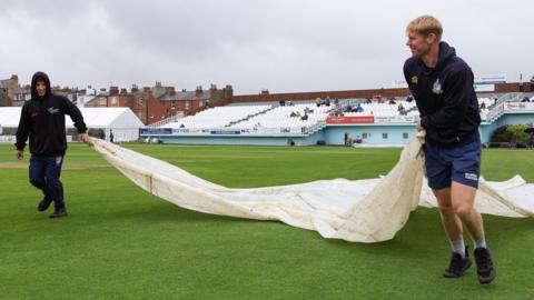 Groundstaff pull on the covers at North Marine Road