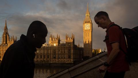 People walk past the Houses of Parliament