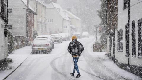 A person walking through a snow flurry in Lenham, Kent.