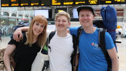 Becky Moriarty, Jared Hill and Rory Leighton in Paddington Station in London, they are travelling by train to the Glastonbury Festival