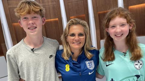William and Harriet stood either side of Sarina Wiegman in the changing rooms at Wembley Stadium