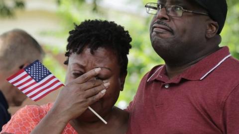 Patricia Olds (L) wipes away tears while visiting a makeshift memorial at the Municipal Center in Virginia Beach.