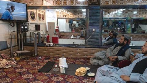 Afghan men watch television in a restaurant in Kabul in August 2022