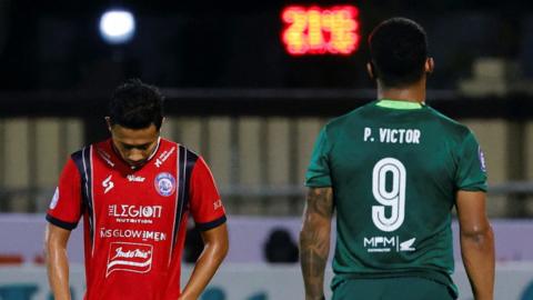 Dendy Santoso of Arema FC reacts as Paulo Victor Costa Soares of Persebaya FC stands during match