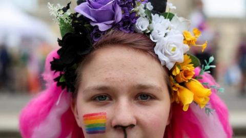 A woman with a pride flag painted on her face