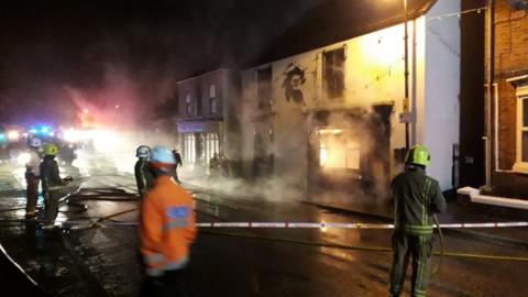 Firefighters in front of a burning building