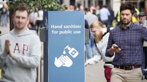 man uses a public hand sanitiser in Leeds city centre