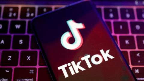 TikTok app logo on phone screen on top of a keyboard