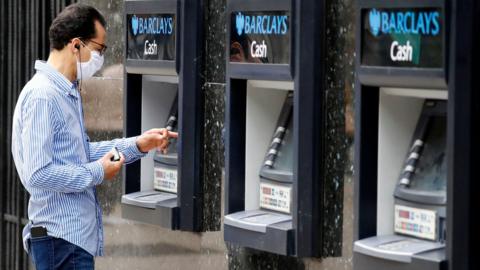 Man using an ATM wearing a face covering