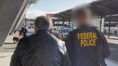 An Australian Federal Police officer (left) and one of the men arrested