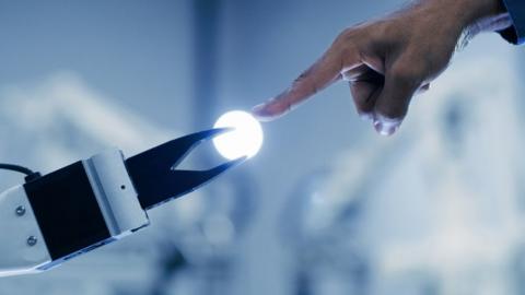 A stock image of a robot holding a bulb and a human touching it - in a pose echoing Michelangelo's The Creation of Adam