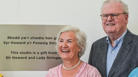 Sir Howard Stringer and his wife Lady Stringer with a plaque in the studio named after them