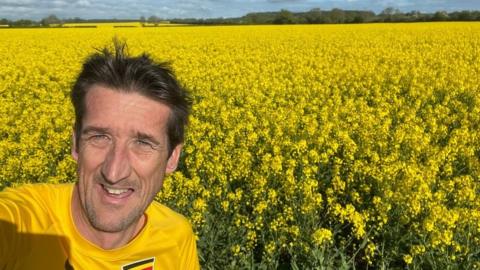 Rob Walker in front of a field of yellow plants