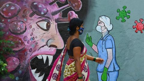 A pedestrian walks past a wall mural depicting a frontline medical staff stopping the Covid-19 coronavirus, in Navi Mumbai in June.