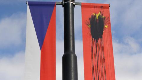 A Czech National flag hangs next to a Chinese National flag splattered with a black substance in Prague on March 26, 2016