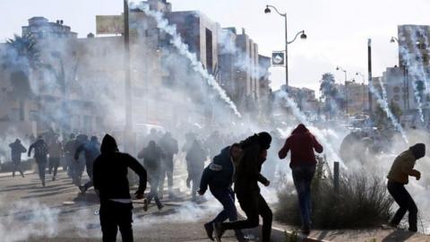 Palestinian protesters run from tear gas near the Jewish settlement of Beit El, near Ramallah