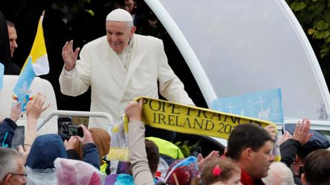 Pope Francis waves to the crowd as he travels in the popemobile to the Knock shrine