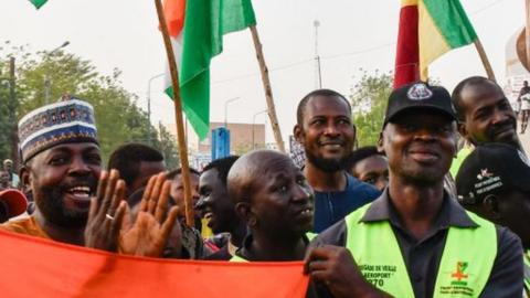 Supporters of the Alliance Of Sahel States (AES) hold up flags as they celebrate Mali, Burkina Faso and Niger leaving the Economic Community of West African States (ECOWAS) in Niamey on January 28, 2024