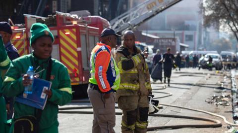 Fire crews, emergency staff and police gather at the site of a fire that broke out at a five-storey building in the city centre, in Johannesburg, South Africa, on 31 August 2023