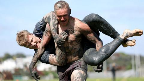 Tristyn Cook of the Blues holds Cam Christie during an Auckland Blues mud run training session at Devonport Naval Base in Auckland, New Zealand