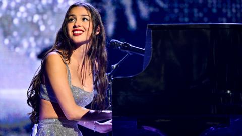 Rodrigo smiles at the crowd as she plays piano on stage