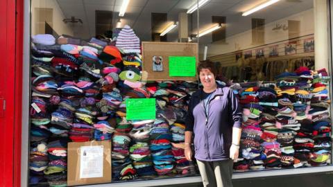 Doreen Armstrong pictured outside the Salvation Army shop in Ballymena and over 3,000 woolly hats