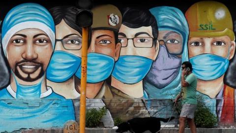 A man walks his dog past a graffiti on a road, amidst the spread of the coronavirus disease (COVID-19), in New Delhi, India, July 17, 2020