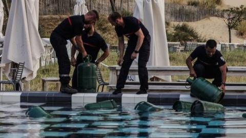 French firefighters fill canisters in a swimming pool