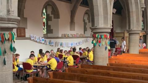 Primary school pupils taking a class in a church