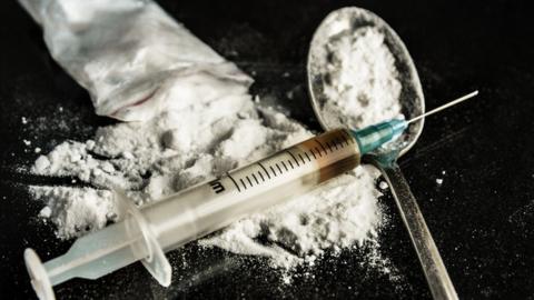 Drug syringe and cooked heroin on spoon