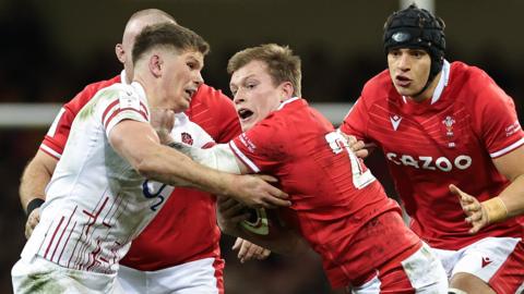 Nick Tompkins of Wales is challenged by Owen Farrell of England