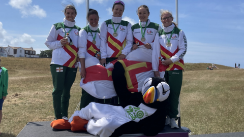 Guernsey's women's squad of Megan Dowinton, Jade Packham, Johanna Petit, Kylie Vaudin, Chloe Woods, with the Islang Games 2023 mascot, Jet the puffin