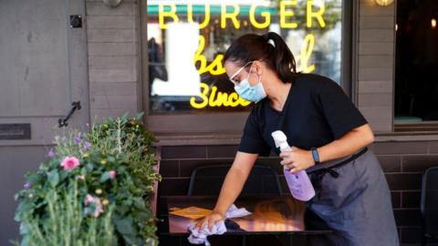 Woman wiping table at burger restaurant