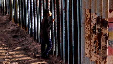 A man looks on through the US-Mexico border wall in Playas de Tijuana, northwestern Mexico in November 2018