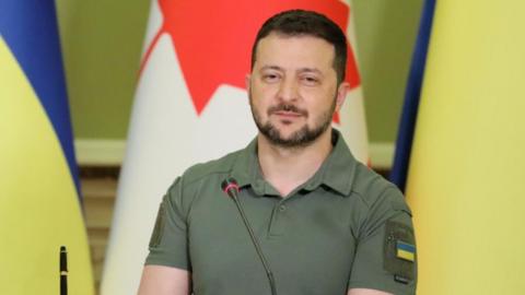 Ukraine's President Volodymyr Zelensky in front of Ukraine and Canada flags