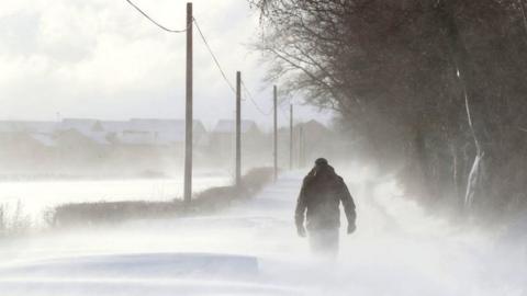 A man walking in snowy conditions in Larbert, Scotland