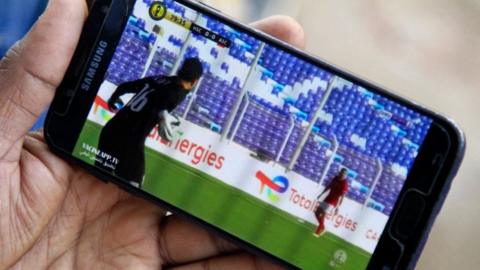 A football fan watching a live game on their phone