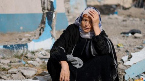 A woman rests next to a damaged building, as Palestinian arrive in Rafah after they were evacuated from Nasser hospital in Khan Younis due to the Israeli ground operation, amid the ongoing conflict between Israel and Hamas, in the southern Gaza Strip, February 15, 2024.