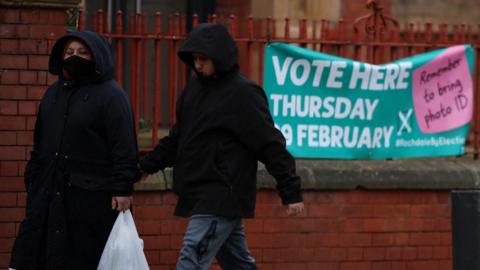 People walk past a banner encouraging voters to take part in the Rochdale by-election (file pic)