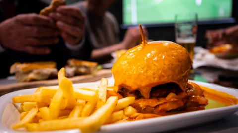 A plate of burger and chips in front of a TV screen