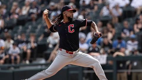 Clase throwing a pitch on the pitcher's mound of a bsaeball field, with his arm swung back and an intense look on his face